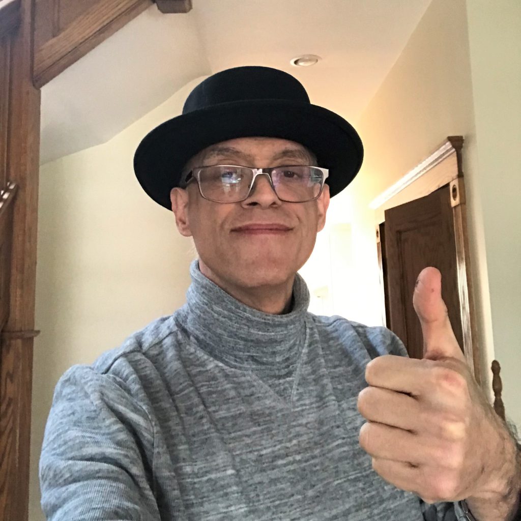 A man with a black hat giving a thumbs-up