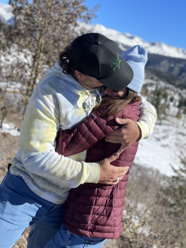 Anna T. and husband Joe hugging snowy mountains